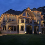 Large stucco estate home with warm white permanent LED lights along the roofline and balconies