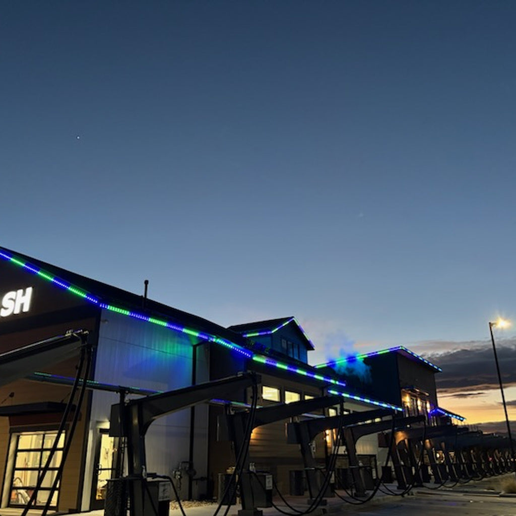 Commercial car wash building with blue and green permanent LED roofline lighting
