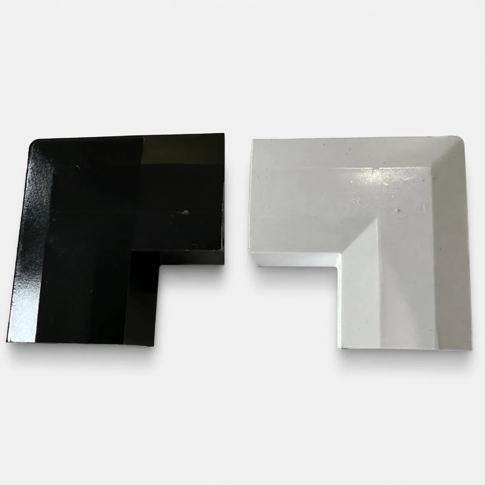 Close-up of black and white permanent LED track corner connectors on a light gray background