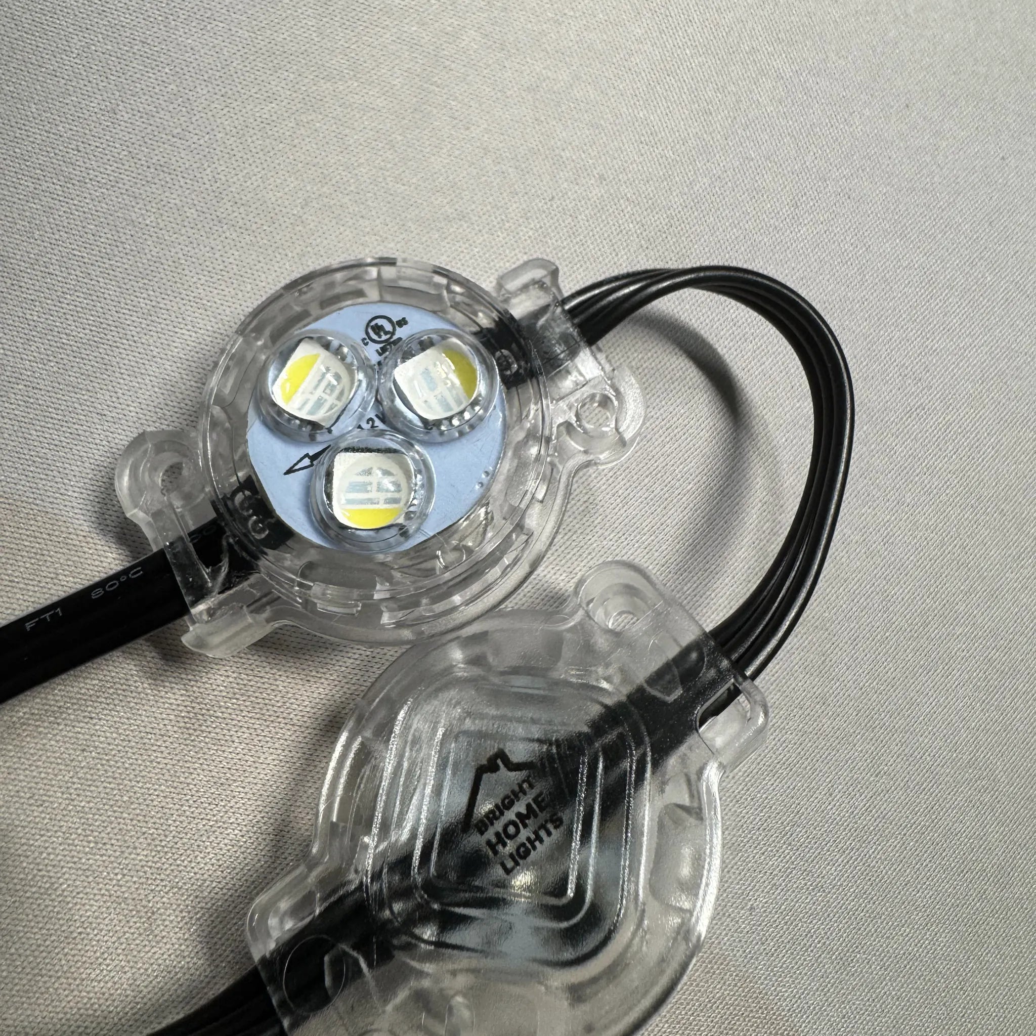 Close-up of RGBW puck light showing built-in mounting holes and clear weather-resistant housing