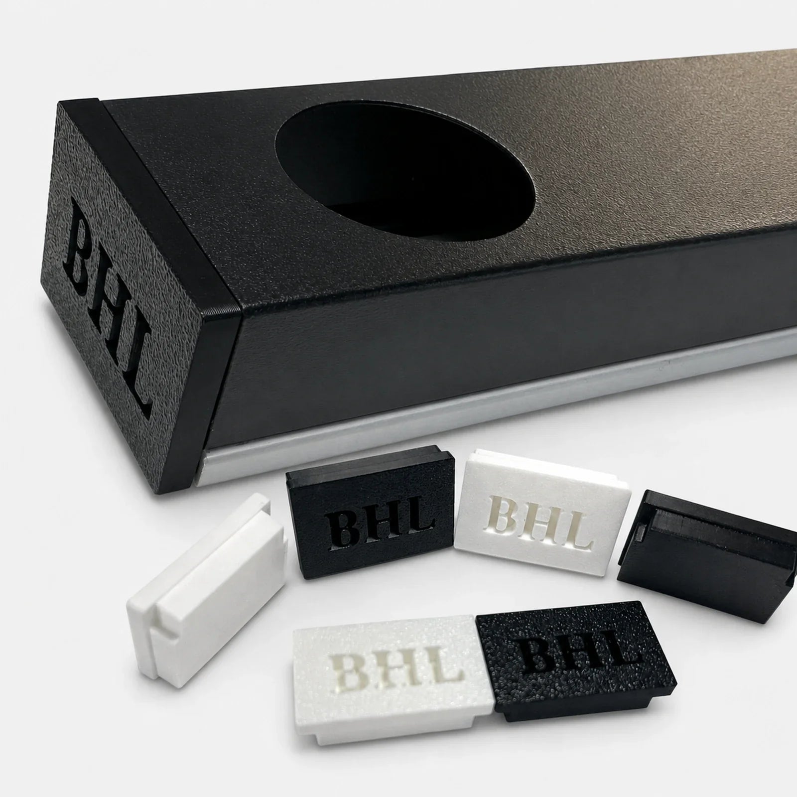 Close-up of a black permanent LED track with installed end cap and loose black and white end caps